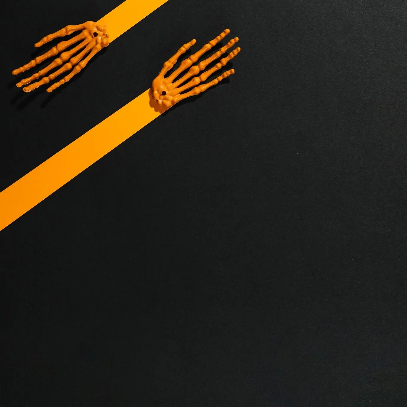 Aus Stücken orangefarbenen Papiers und Knochen hergestellte Skelett-Hände.